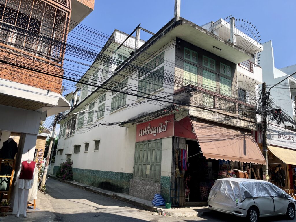 ワロロート市場の古い建物、白い壁と淡いグリーンの窓が並ぶ