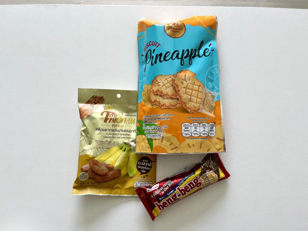 机上に干しバナナ・ビスケット・チョコレートウエハースのローカルなお菓子が並んでいる