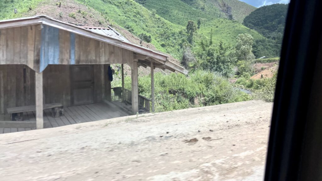 ラオスの山間部の舗装されていない道路を、車窓から写す