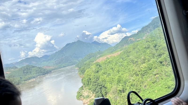 列車からの車窓、メコン川と木々が生い茂る山々が見える