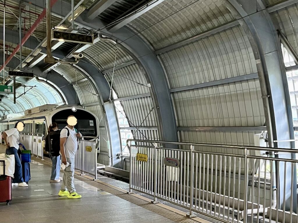 ARL（エアポート・レール・リンク）のマッカサン駅に列車が到着、荷物を持った観光客が並ぶ
