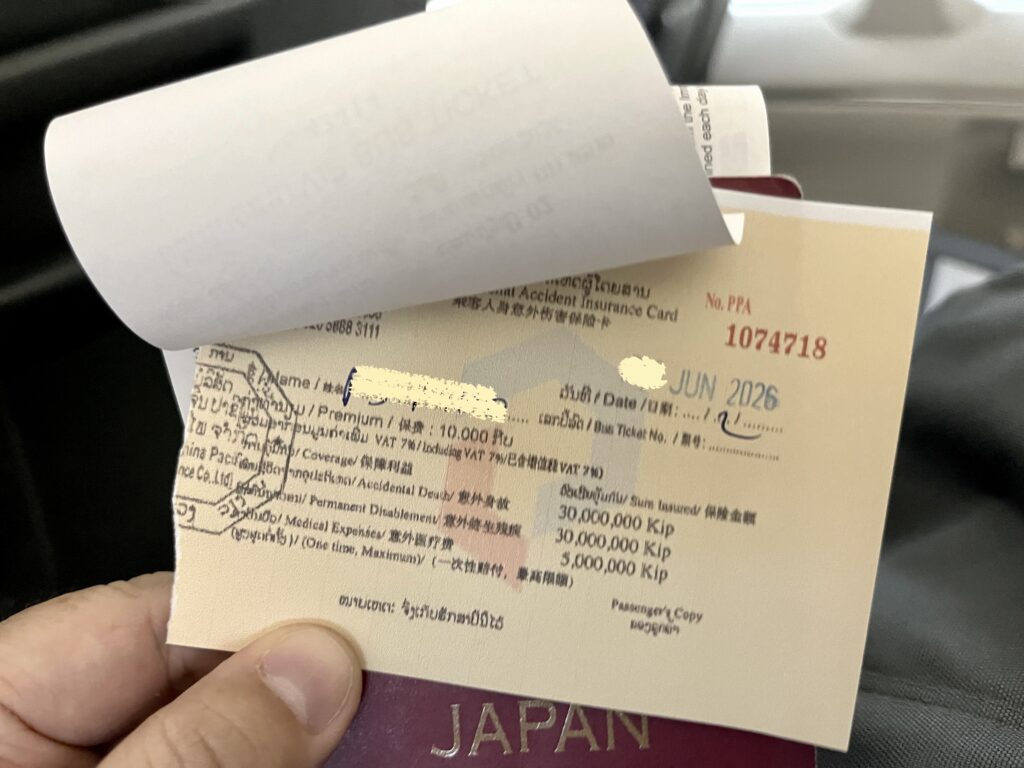 手に持ったラオスの傷害保険の加入証書と日本のパスポート