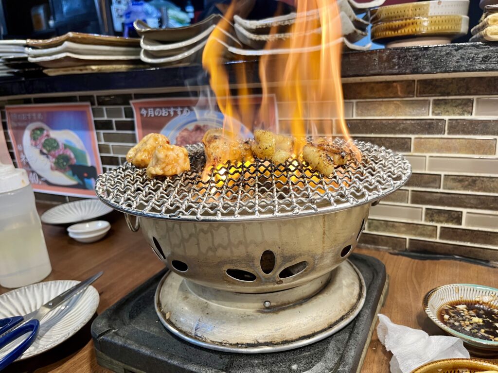 日本街(にほんまち/Nihonmachi)にあるおにくとごはん。の卓上コンロでホルモンを焼いている、炎が激しい