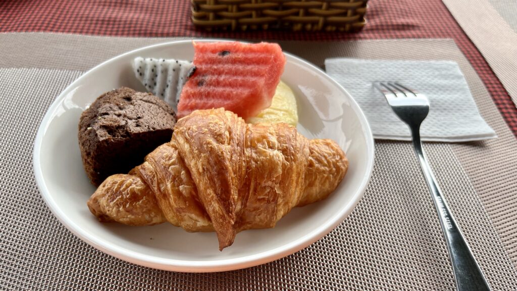 Merry Riverside Hotelの朝食会場、テーブルに置かれた皿にクロワッサンや果物が盛られている