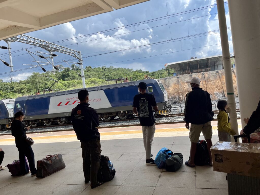 中国ラオス鉄道のナトゥイ駅のプラットホームで列車を待つ人々