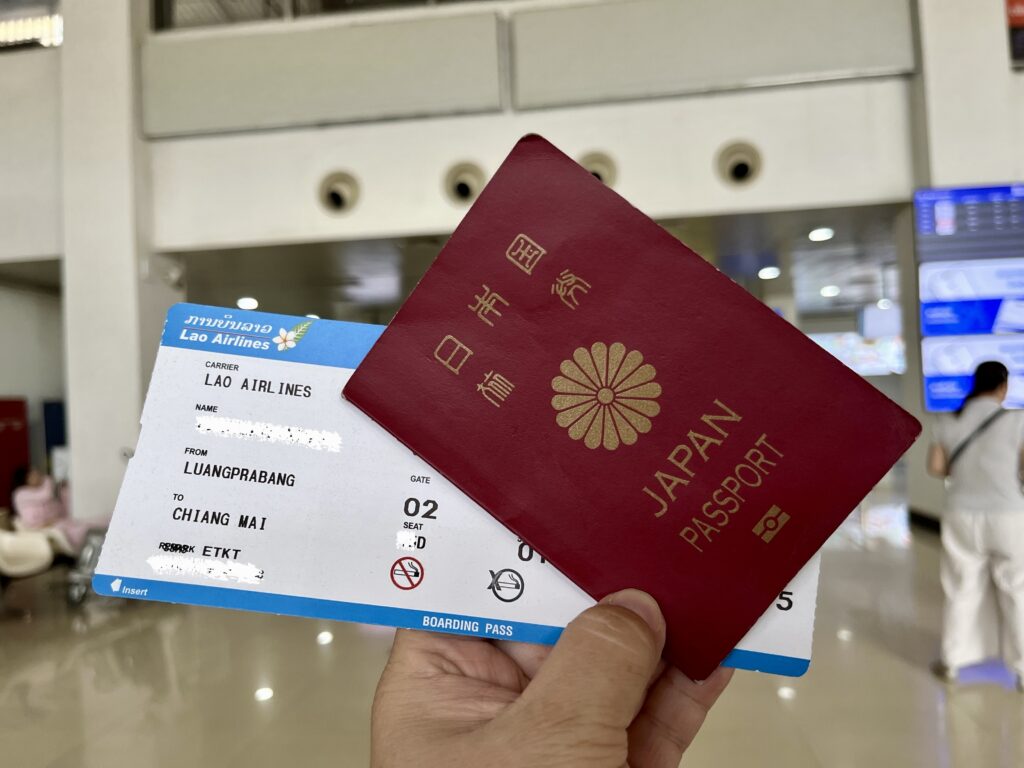 左手で、ラオス航空のチケットと日本のパスポートを持つ