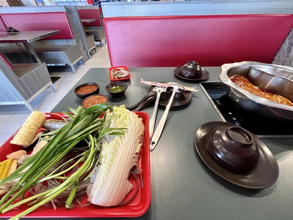 テーブル上に火鍋と、野菜がたくさん盛られてたトレーが置かれている