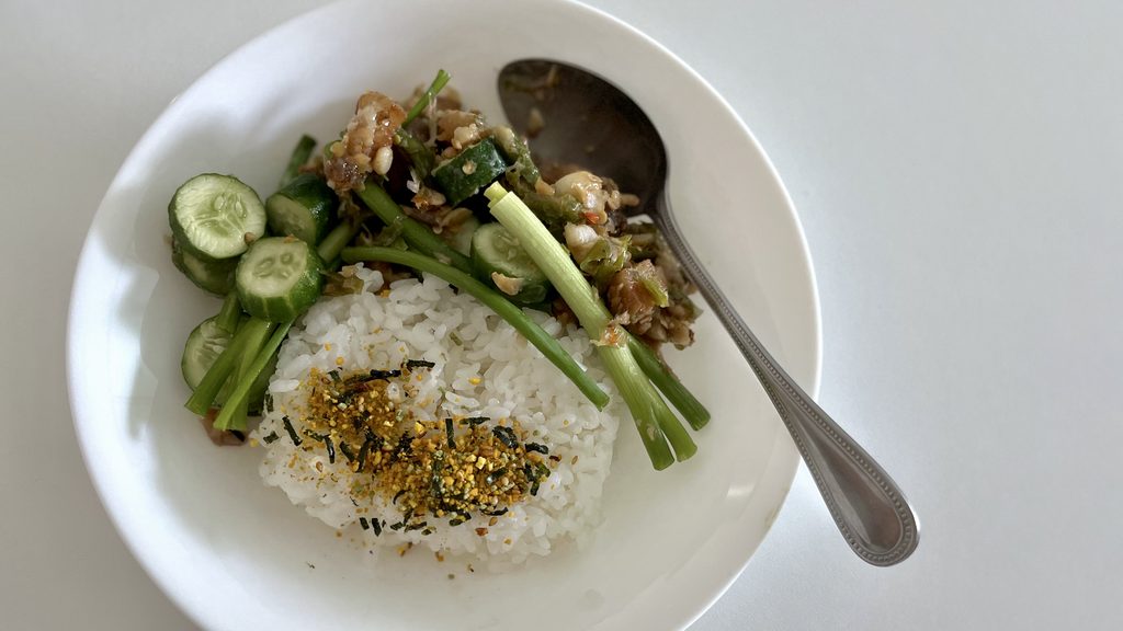 お皿に豚バラ肉とスアン種生唐辛子(プリックキーヌー)炒め掛けごはん(カオ・ラート・ムーサムシャン・パット・プリックキーヌー・スアン ข้าวราดหมูสามชั้นผัดพริกขี้หนูสวน)がよそられている