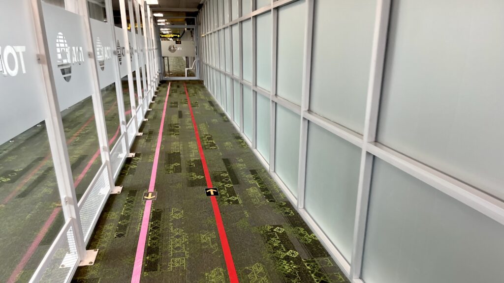 チェンマイ国際空港の搭乗口を出たところにある国際線と国内線を結ぶ通路、赤とピンクの線が床に引いてある